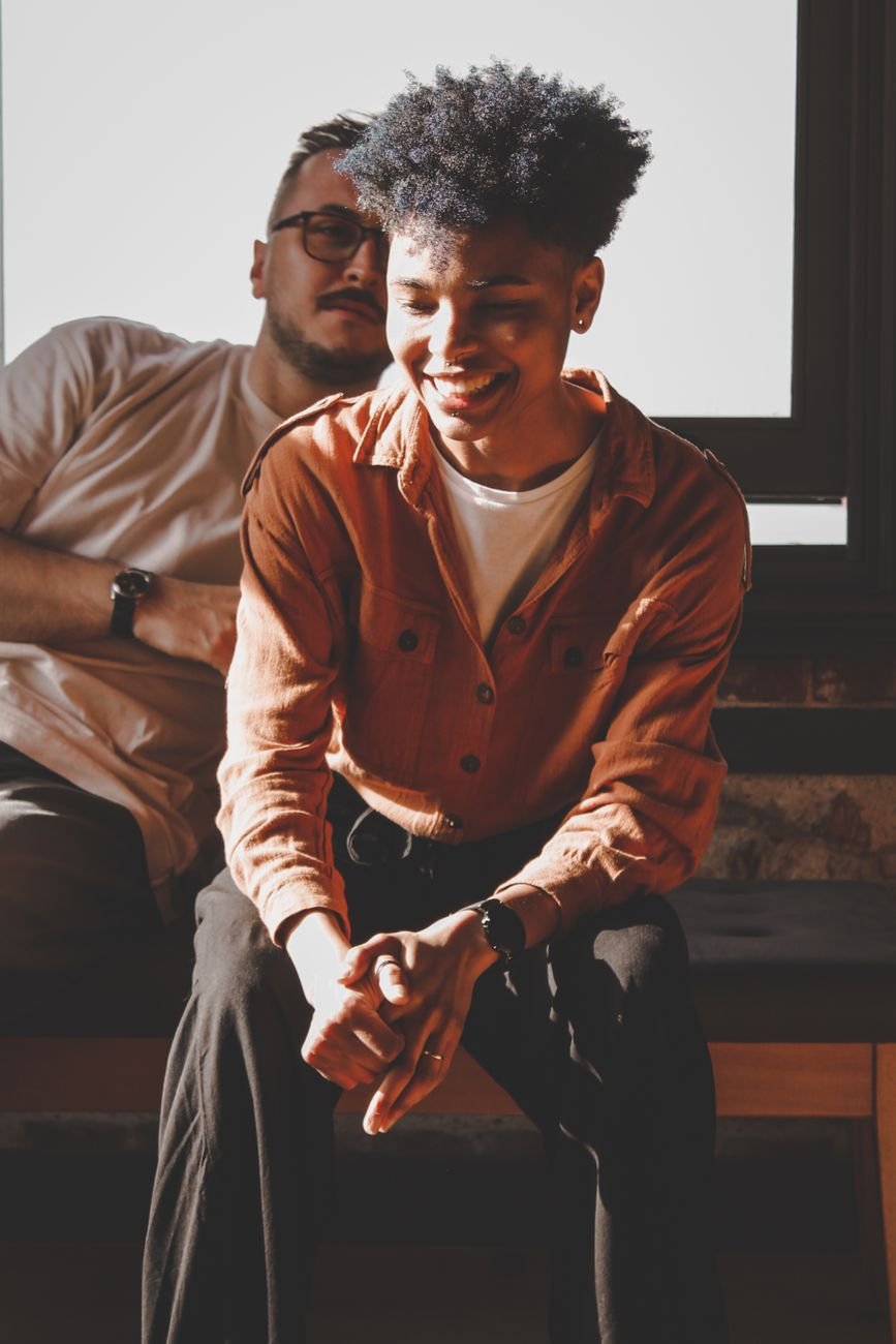 Two friends laughing together in warm sunlight — comedy genre