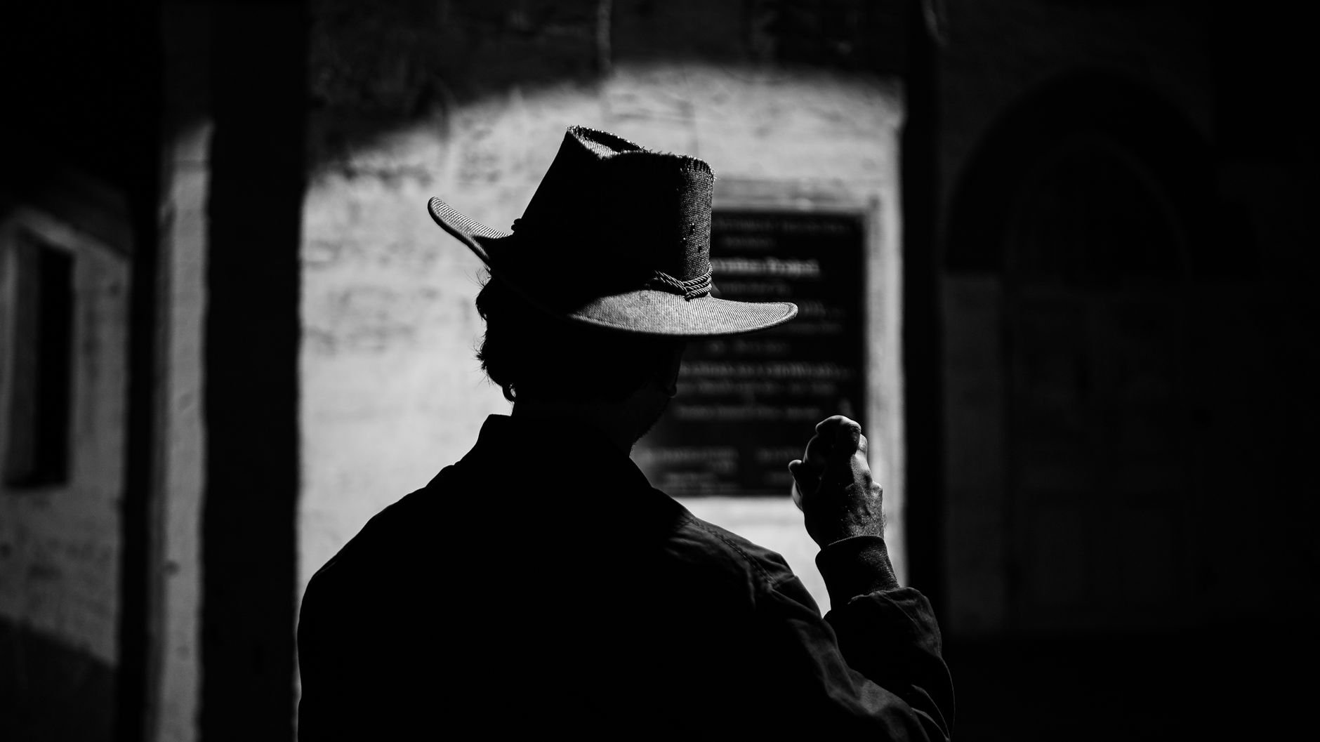 Dramatic black and white silhouette of a man holding an object in a dark alley