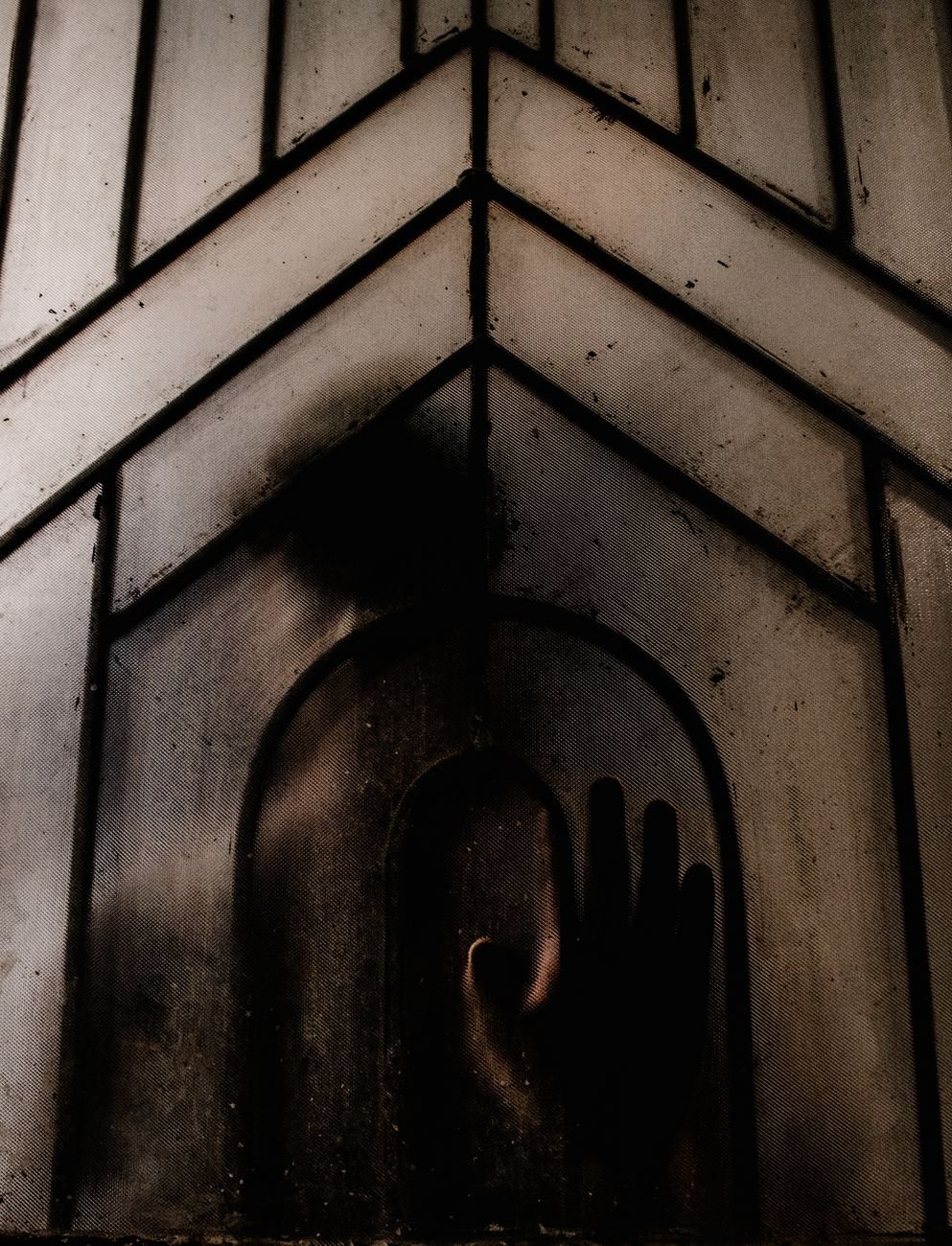 Mysterious silhouette pressing against a frosted window — thriller genre